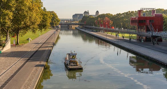 photo of La Villette Park with the Canal of the Basin of the Villette with boat at beautiful morning in Paris, France.