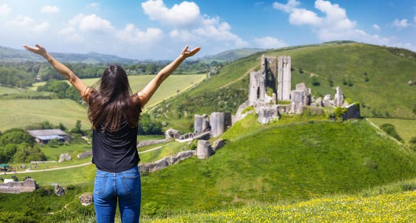 Photo of a tourist woman looks at the ruins of Corfe Castle, Dorset, England.