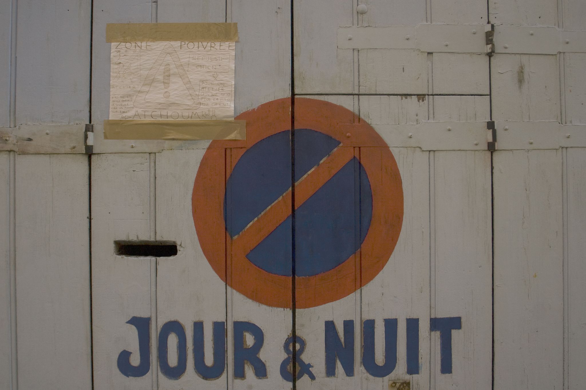 Hand-painted no parking sign with -Jour & Nuit- text on a garage door in Marseille, France..jpg