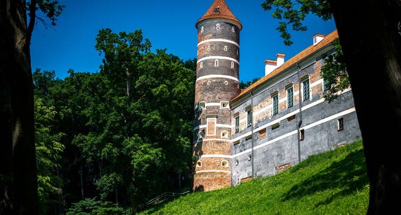 Panemune Castle with green trees and blue sky. Castle on the right bank of the Nemunas river, in Vytėnai, Jurbarkas district, Lithuania. One of the most beautiful Renaissance era building in Lithuania