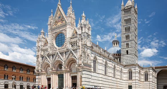 Photo of Siena cathedral against a bright blue sky in Italy.
