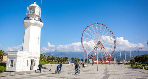 Photo of Ferris wheel and Batumi lighthouse on the Batumi Seafront Promenade on a sunny day, Georgia.