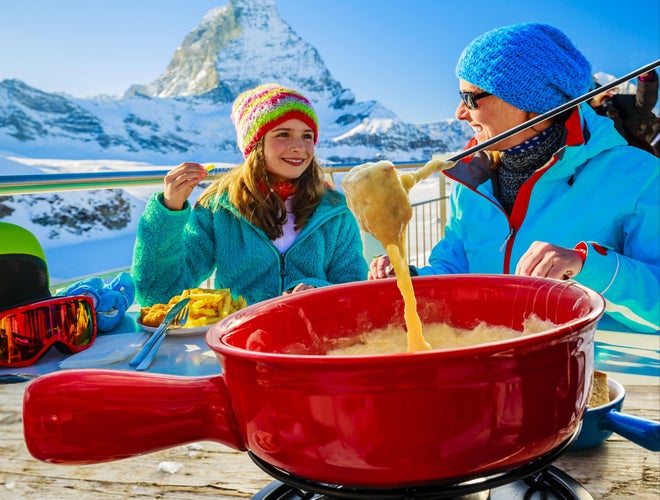 Family enjoying Swiss cheese fondue outdoors with a view of the Matterhorn in Zermatt..jpg