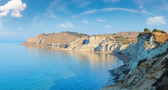 Photo of sandy beach under famed white cliff, called "Scala dei Turchi", in Sicily, near Agrigento, Italy.