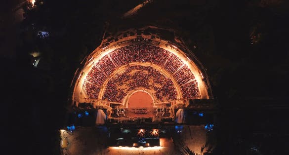 Photo of aerial birds eye view night shot taken by drone of iconic Odeon of Herodes Atticus full of people attending a concert, Athens historic center, Attica, Greece.
