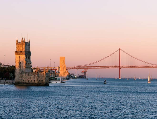 Belem Tower and 25 de Abril Bridge at sunset, a scenic view of Portugal in August..jpg