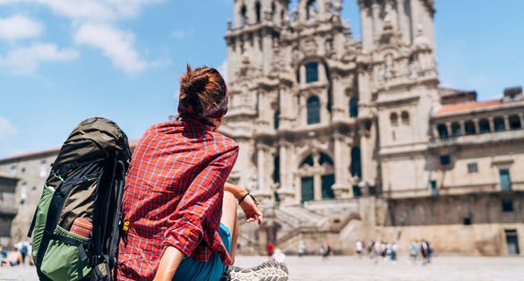 Photo of woman tourist piligrim siting on the Obradeiro square (plaza) in Santiago de Compostela.