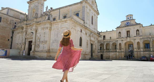 Beautiful young woman walking in the Cathedral Square of the Baroque City of Lecce, Salento, Italy