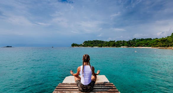Photo of girl sitting in yoga pose at the Pier at Rovinj, Croatia.