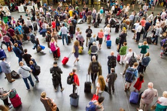 Busy crowd of travelers with luggage inside a London train station during peak summer travel season..jpg