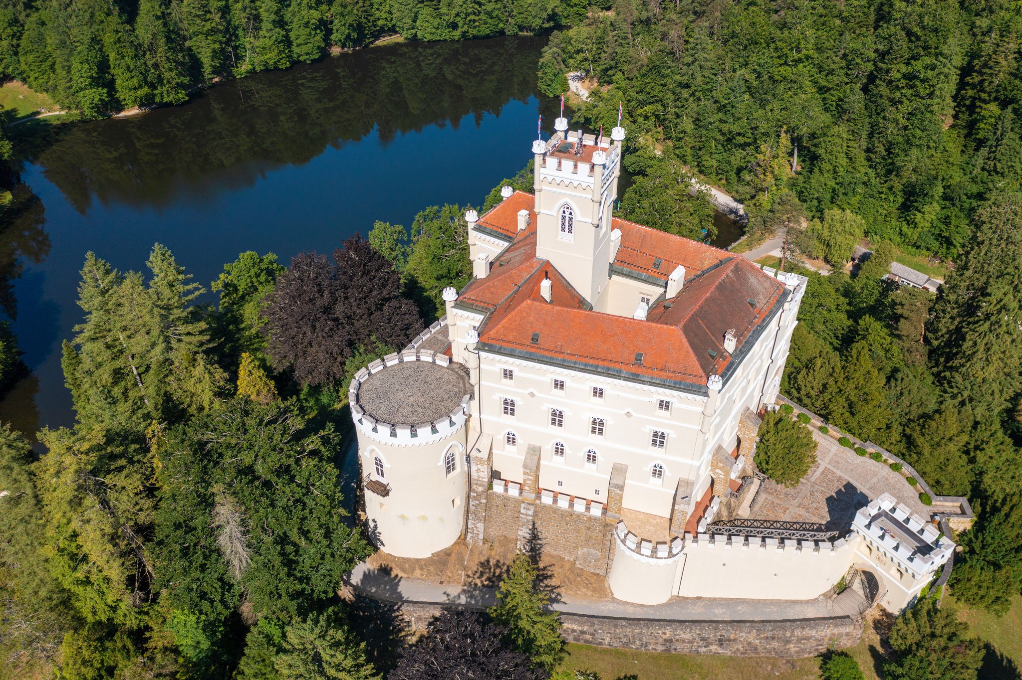 Photo of aerial view of Trakoscan castle surrounded by the lake and forested hills, rural Croatia.