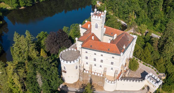 Photo of aerial view of Trakoscan castle surrounded by the lake and forested hills, rural Croatia.