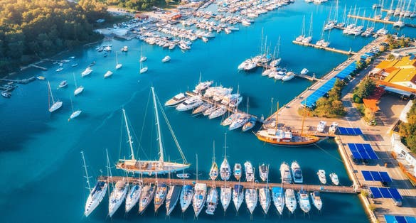 Photo of aerial view of boats and luxury yachts in dock at sunset in summer in Pula, Croatia.