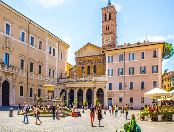Travelers walking through Piazza di Santa Maria in Trastevere in Rome on a sunny day..jpg