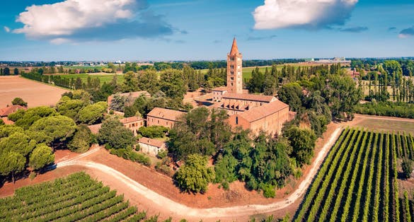 Wonderful summer view of Pomposa Abbey tower among the green vineyards. Attractive morning scene of Italian countryside, Province of Ferrara, Italy, Europe. Traveling concept background.