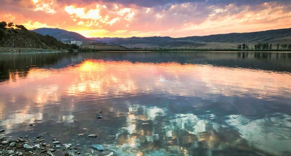 photo of Lisi lake panorama with reflections of dramatic sky and sunset over the horizon. Lakes and leisure in Tbilisi, Georgia.