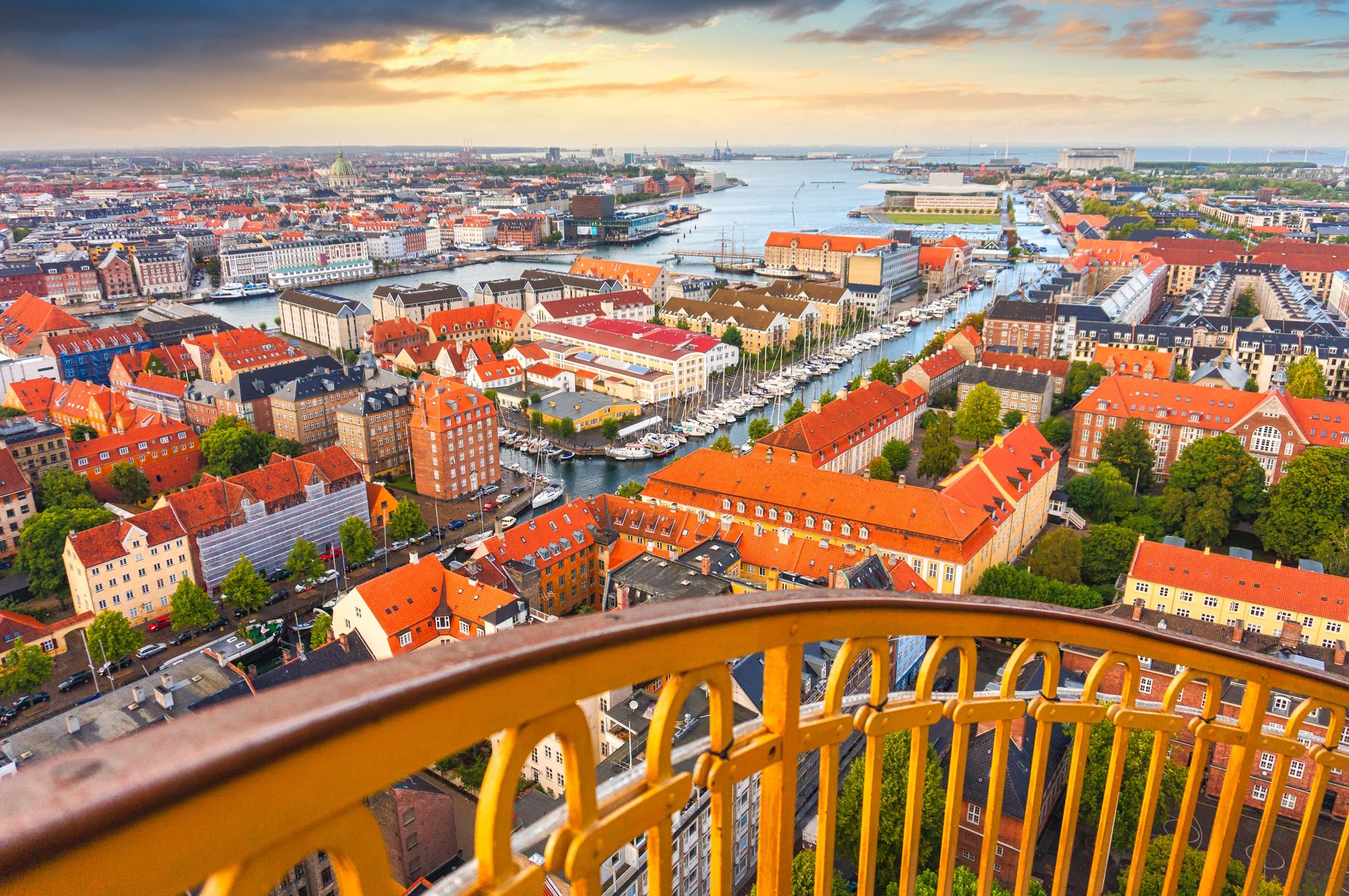 Photo of skyline of Copenhagen from external winding staircase to the top of church of Vor Frelsers Kirke during sunset, Copenhagen, Denmark.