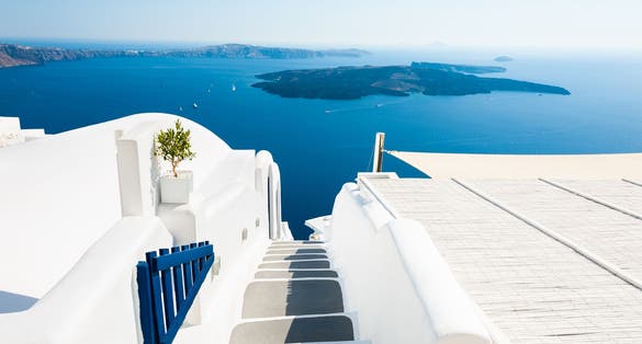 Photo of traditional narrow street with stairs leading to the beach in Oia village, Santorini Island, Greece.