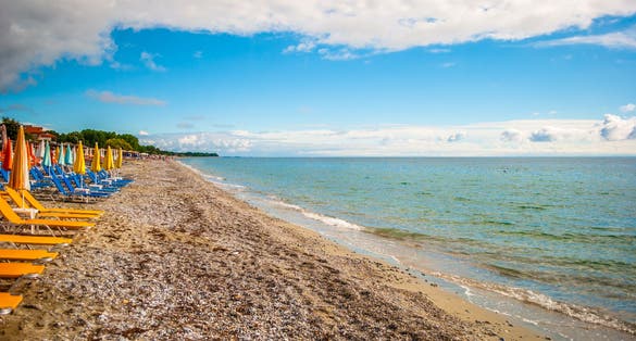 Photo of The sea shore of Leptokarya, with blue sky and clouds and clear sea.