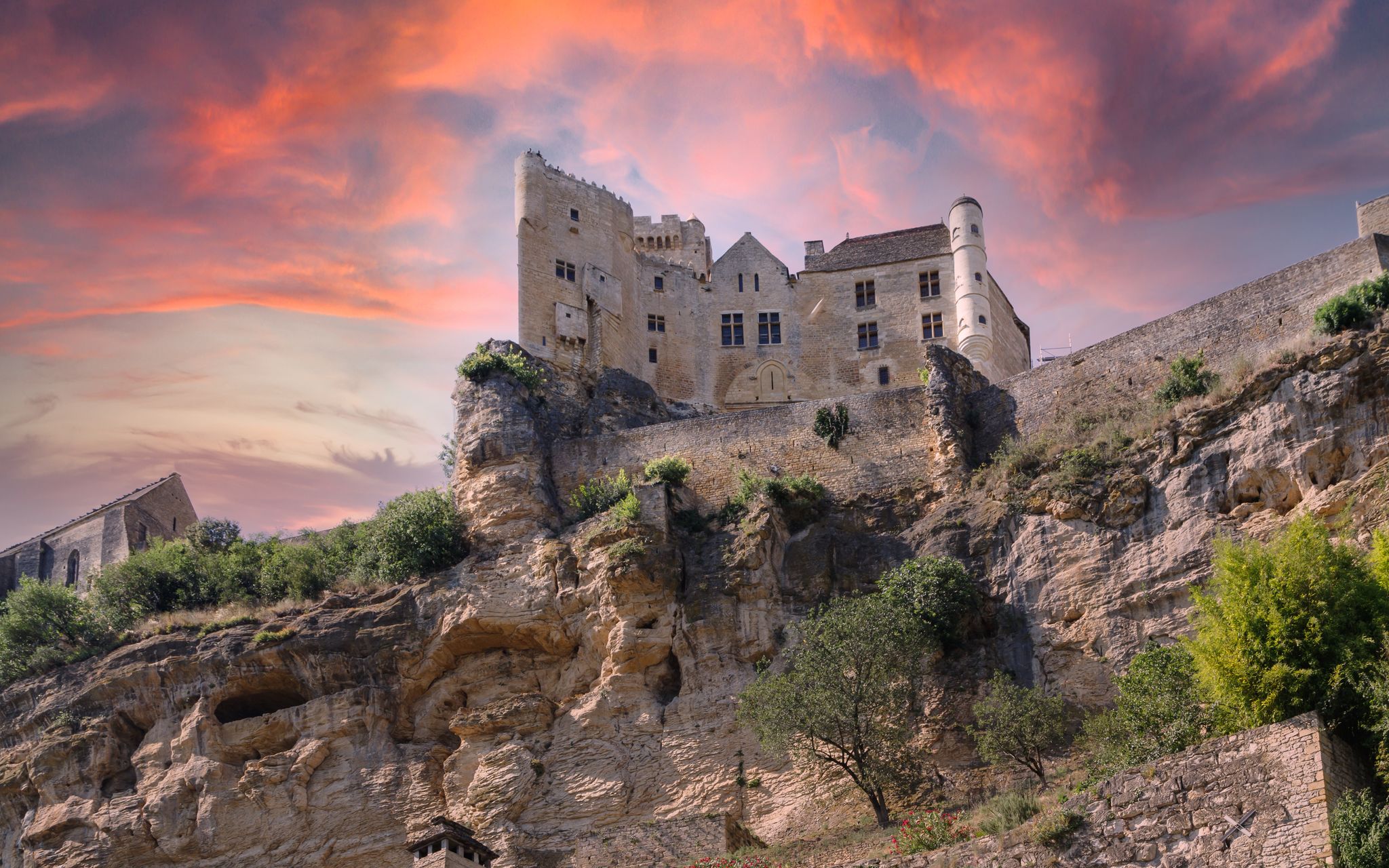 photo of Chateau de Beynac on the rock against dramatic sunset sky in Village of Beynac-et-Cazenac, France.