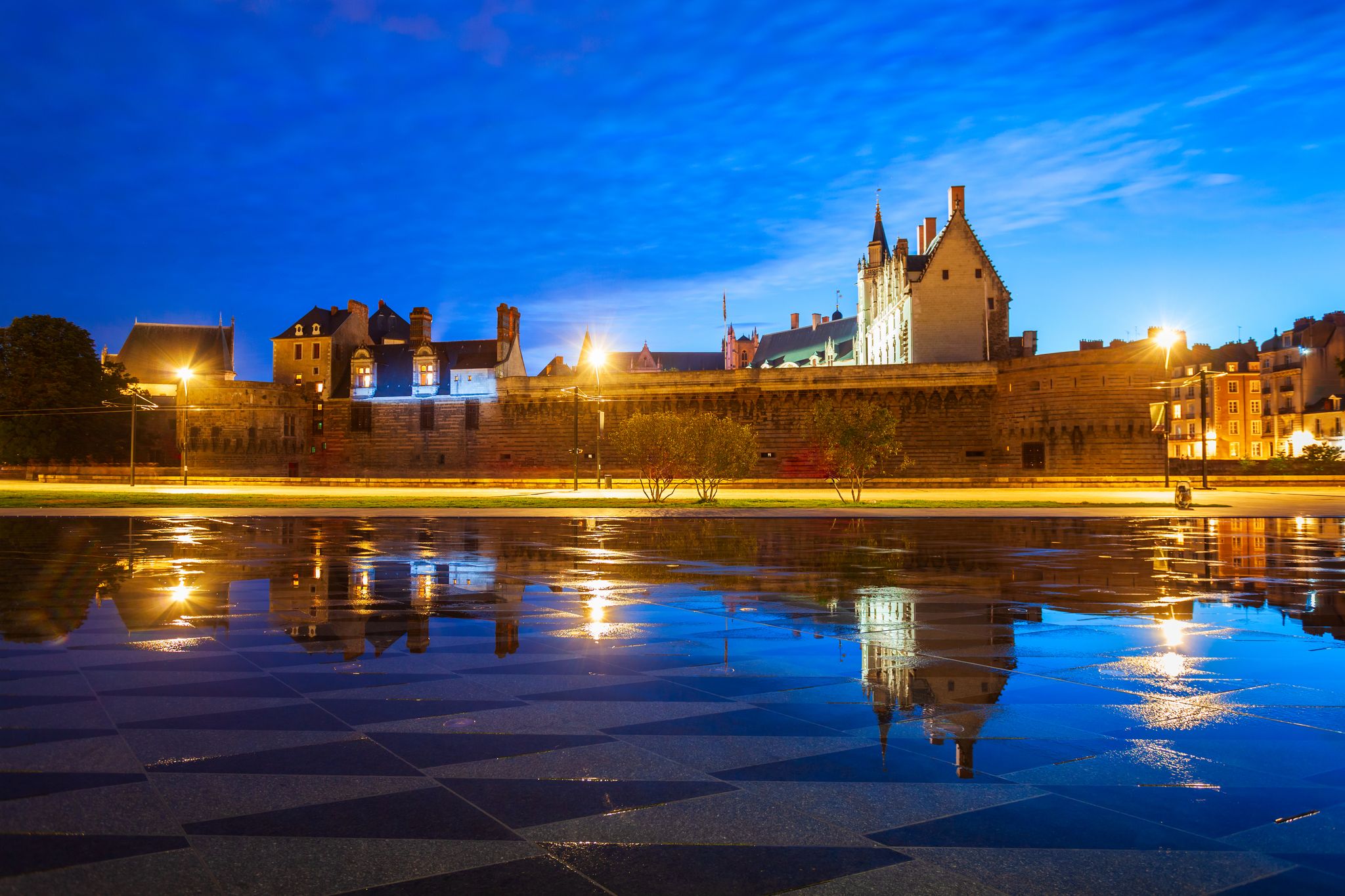 photo of the castle of Dukes of Brittany with water mirror (Miroir d'eau) at night in Nantes city in France.