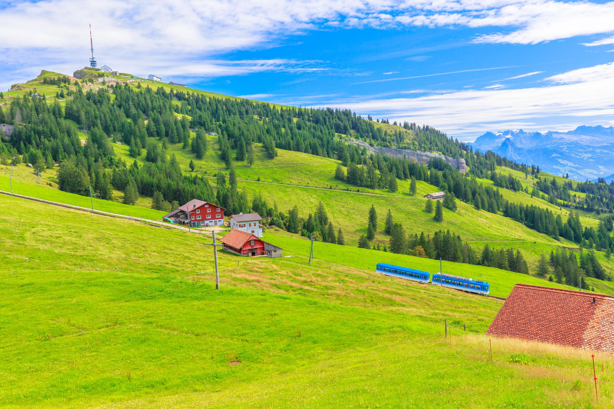 photo of scenic landscape between Alps, valleys of Rigi Mountain railways and blue cog train in Rigi Kulm in Arth, Switzerland.