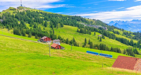 photo of scenic landscape between Alps, valleys of Rigi Mountain railways and blue cog train in Rigi Kulm in Arth, Switzerland.