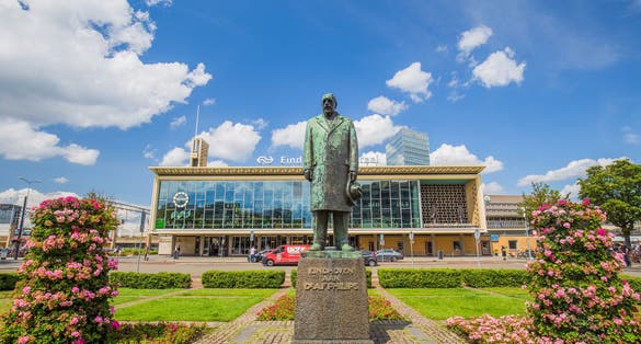 Eindhoven, Netherlands- July 26, 2023: The Central train station of Eindhoven and bus station with in front a statue of Anton Philips. dutch city on a sunny day with blue sky and beautiful clouds.