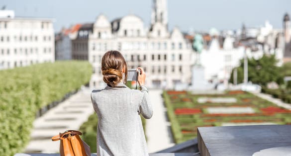 Photo of female traveler standing with photocamera on the famous Arts mountain with great view on the old city in Brussels