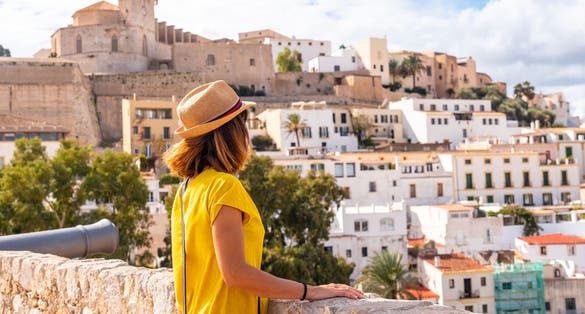 Photo of woman tourist looking at the cathedral of Santa Maria de la Neu from the castle wall of Ibiza.