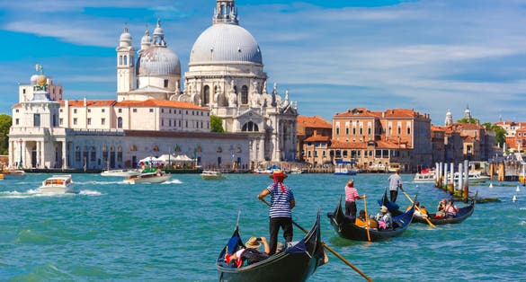 photo of Picturesque view of Gondolas on Canal Grande with Basilica di Santa Maria della Salute in the background, Venice, Italy. Selective focus on Gondolier .