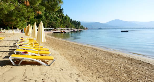 Photo of beautiful beach with sunbeds and umbrellas on turkish resort, Fethiye, Turkey.