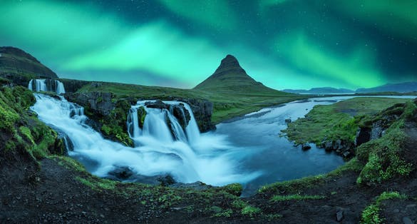 photo of aurora borealis northern lights over kirkjufellsfoss waterfall. Amazing night scene near kirkjufell volkano, Iceland. Landscape photography panorama.