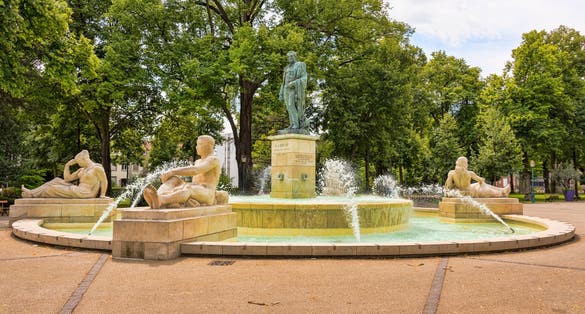 Photo of the "Bruat Fountain" with its sandstone figures and a bronze statue of Admiral Bruat on Mars field in the French city of Colmar in Alsace.