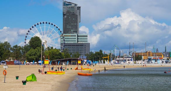 Photo of Water fountain in public park with view of tall tower building, Gdynia city waterfront, Poland