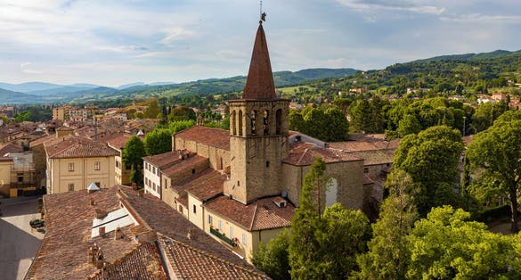 Panorama of the medieval town of Sansepolcro, Tuscany, Italy, with St.Francis (San Francesco) Church's bell tower, typical red roof tiles, cloudy sky and tuscanian hills in the distance.