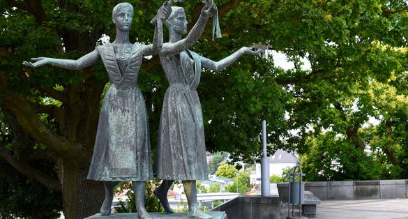Two statues of young women with flowers in their hands at Slavin War Memorial Monument.