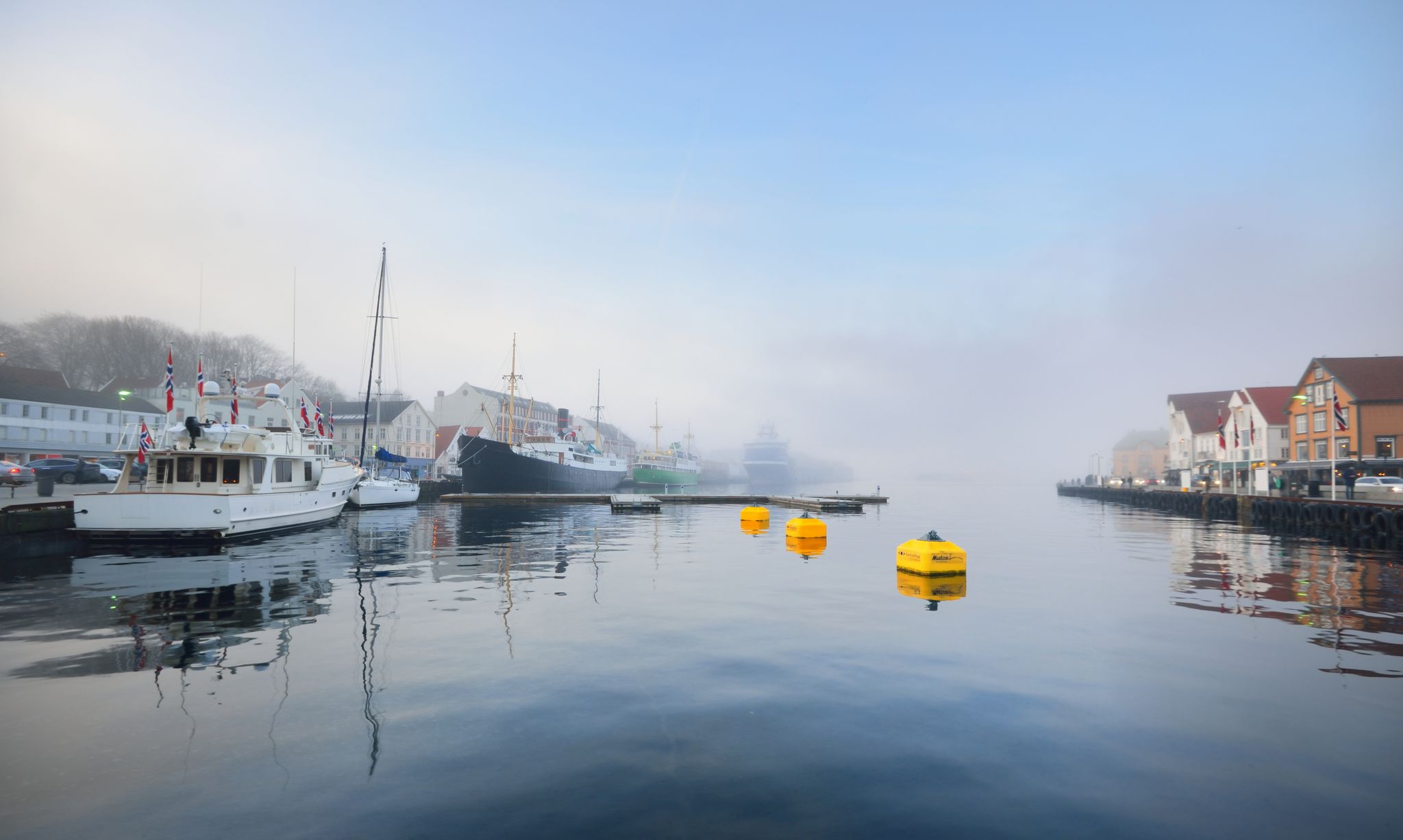 Old passenger ship and yachts moored to a pier in a city center. Stavanger embankment, Norway. Travel destinations, tourism, sightseeing, landmark, cruise, recreation, transportation, nautical vessel