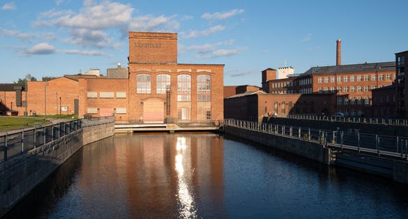 Photo of Vapriikki Museum, Tampella building. View over Tammerkoski river in warm sunlight, Tampere, Finland.