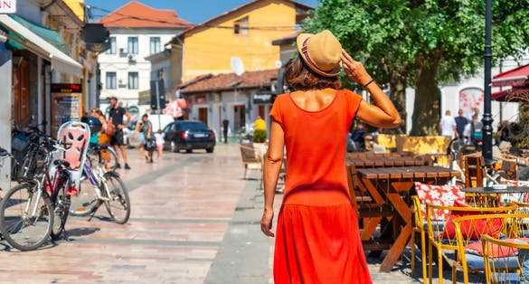 photo of Tourist woman in red dress and hat enjoying vacation walking on the streets of Shkoder city. Albania.