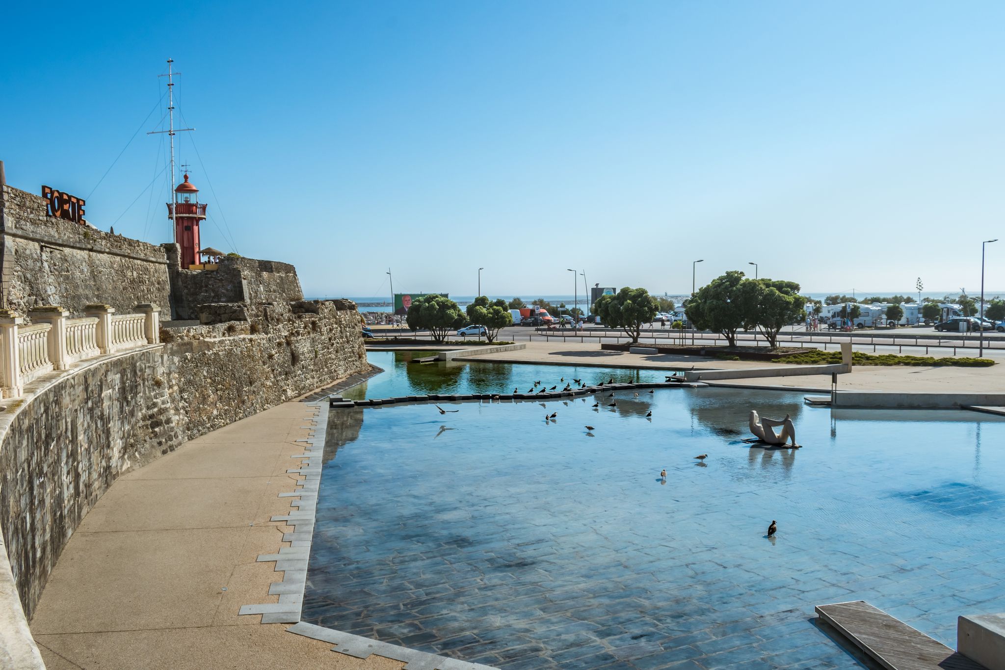 Photo of Perspective of the wall of the Santa Catarina fort with a small lake and birds in Figueira da Foz, Portugal.