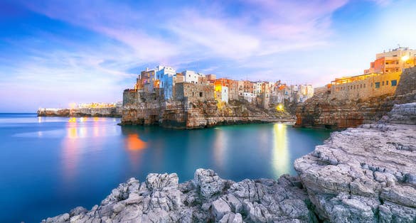Sunset at Cala Paura gulf with Bastione di Santo Stefano in village on the rocks Polignano a Mare, Apulia, Italy, province of Bari.