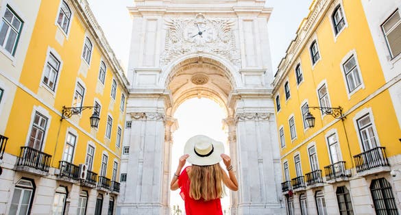 Photo of Young woman tourist standing back in front of the famous triumphal arch in Lisbon city center in Portugal.