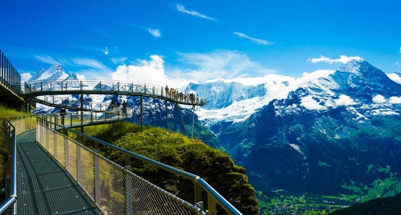 photo of people watching the beautiful view from a cliff walk and an observatory of the First of Grindelwald, Switzerland.