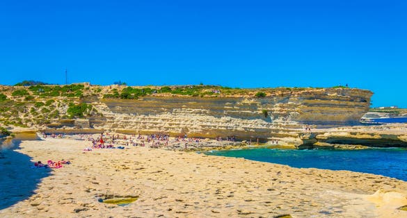 Photo of crystal clear turquoise water in blue lagoon of St. Peters pool  rocky beach at Malta.