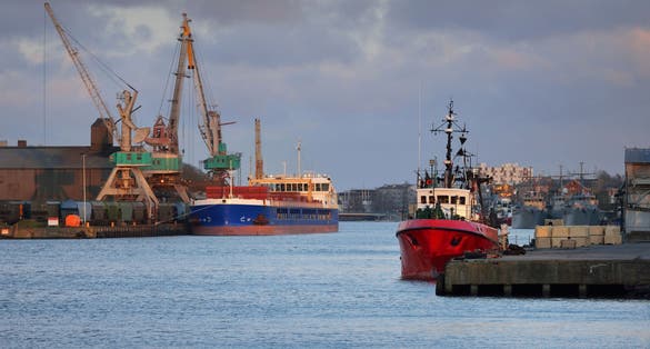 photo of view of anchored in a trading port. Cranes in the background. Liepaja, Latvia, Baltic sea. Freight transportation, logistics, global communications, industry, economy