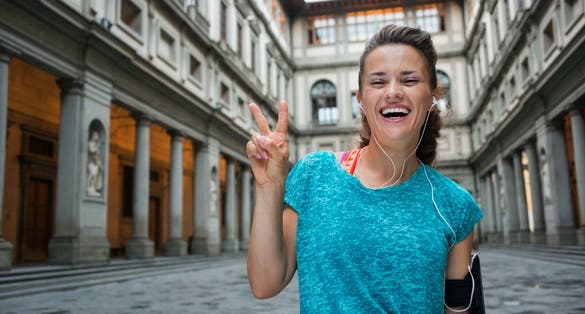 photo of happy fitness woman showing victory gesture near uffizi gallery in florence, italy.