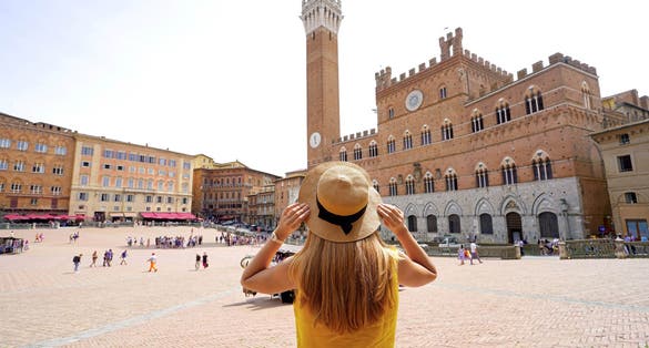 photo of holidays in Tuscany. Back view of beautiful woman visiting main square of Siena, Italy.