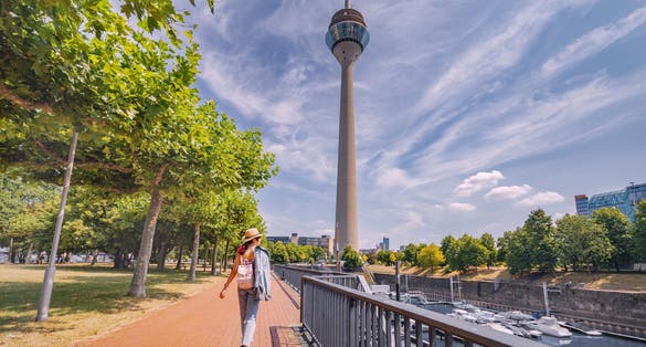 Photo of  girl traveler enjoys a beautiful view in the Media Bay harbor and marina with TV-tower in Dusseldorf, Germany.