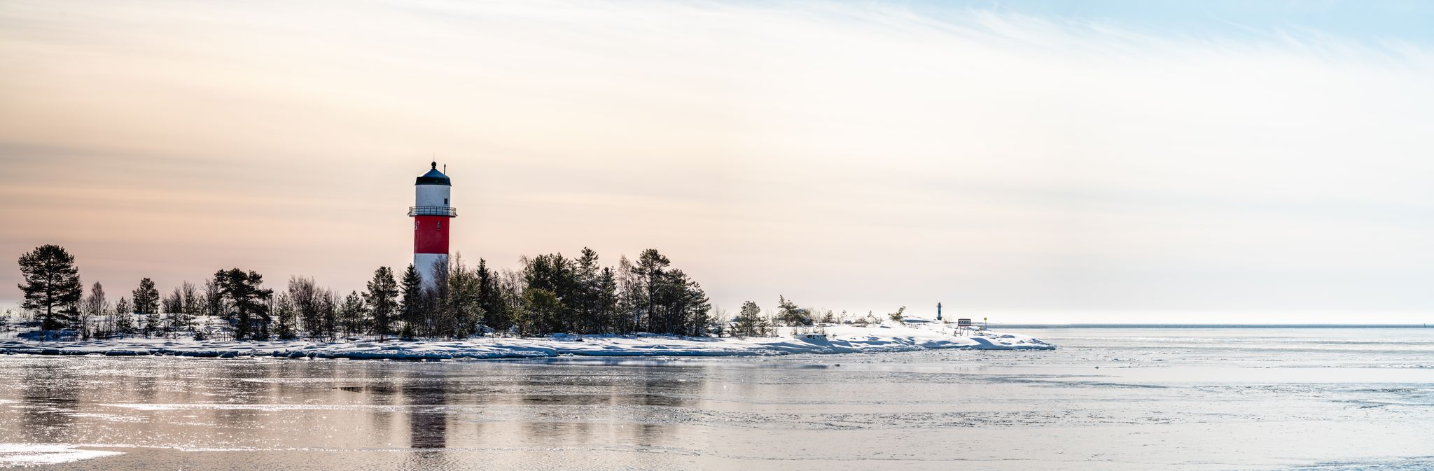 Panorama, close view of red and white lighthouse in middle of frozen island, Northern Sweden, Umea.